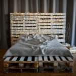 Modern interior. The bed is made from pallets, decorated with garlands and gifts.