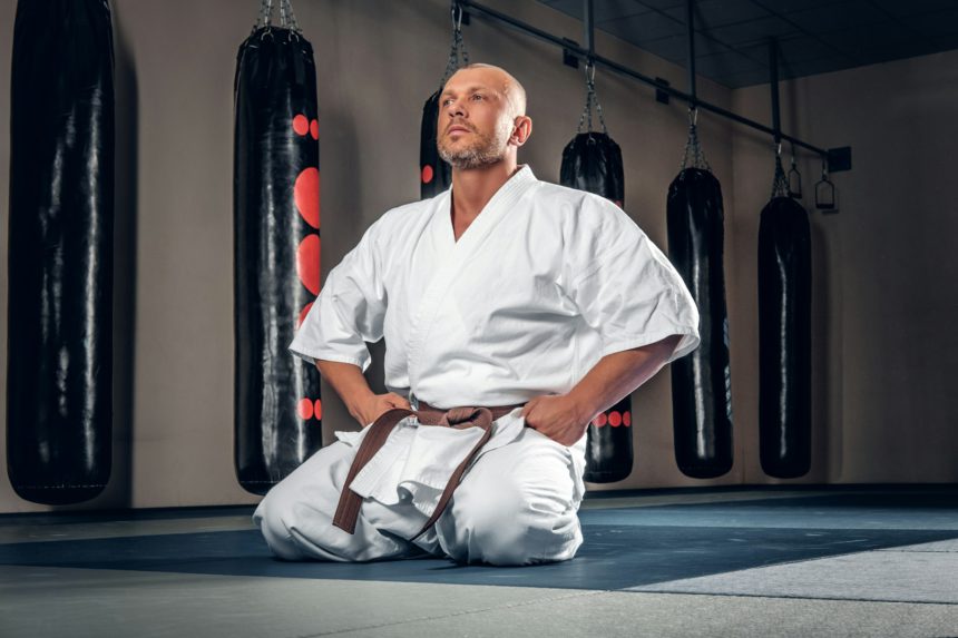 Shaved head karate fighter in a gym.