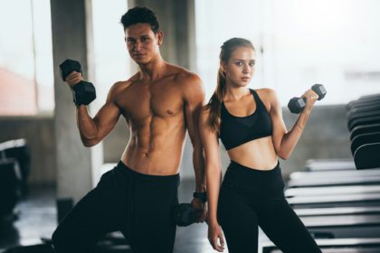 Sporty young couple with dumbbells in functional training fitness gym